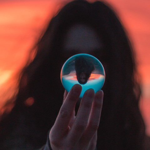 Κοπέλα κρατάει γυάλινη μπάλα με αντανάκλαση του εαυτού της