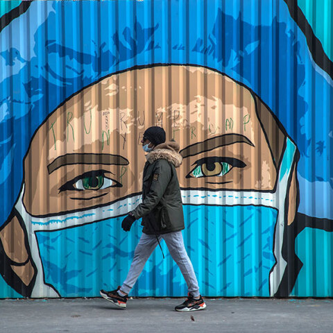 Πολίτης με μάσκα για τον κορωνοϊό μπροστά από mural για την πανδημία Covid στο Παρίσι