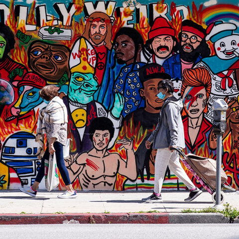 Πολίτες με μάσκα για κορωνοϊό στο Λος Άντζελες μπροστά από mural για το Χόλιγουντ