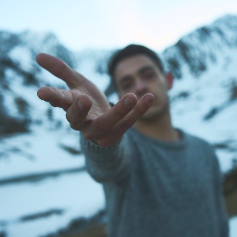 Άνδρας σε χιονισμένο τοπίο που απλώνει το χέρι του