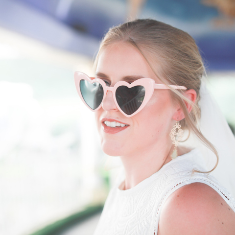 Ξανθιά κοπέλα ντυμένη νύφη με γυαλιά ηλίου σε σχήμα καρδιάς