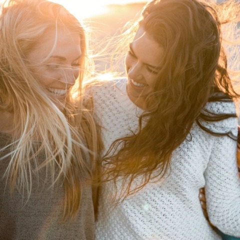 Δύο φίλες που γελούν στην παραλία.