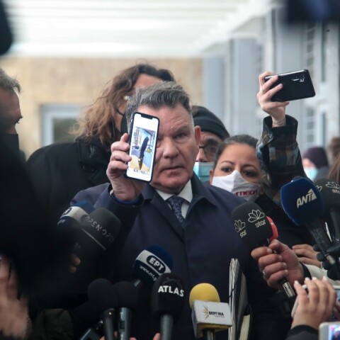 Ο Αλέξης Κούγιας με τη φωτογραφία που έδειξε στους δημοσιογράφους με ένα μαχαίρι καρφωμένο σε ένα τραπέζι