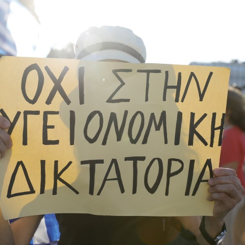 Γυναίκα που κρατά πλακάτ σε συγκέντρωση αντιεμβολιαστών