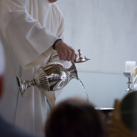 Ιερέας χύνει νερό στη κολυμβήθρα για την τέλεση της βάπτισης