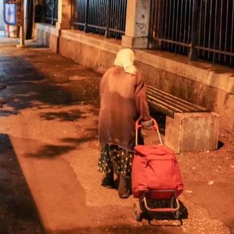 Ηλικιωμένη σέρνει το καρότσι της σε δρόμο 