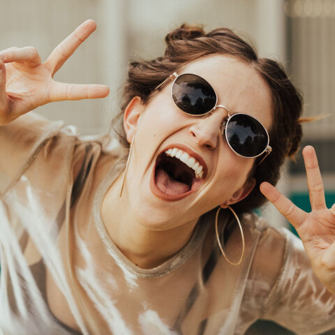 Κοπέλα με γυαλιά ηλίου που γελάει στην κάμερα