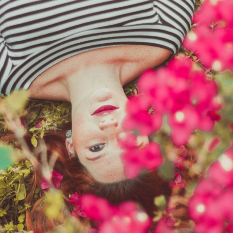 Ένα κορίτσι ποζάρει κάτω από λουλούδια. 