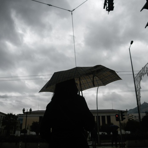 Κακοκαιρία: Γυναίκα κρατά ομπρέλα για να προστατευτεί από την καταιγίδα
