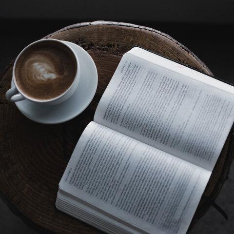 Ανοιχτό βιβλίο σε τραπεζάκι με φλιτζάνι καφέ δίπλα