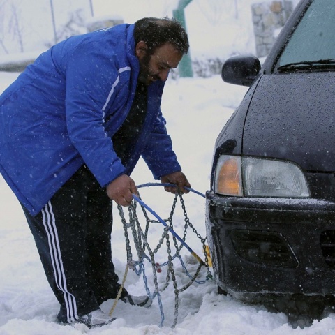 Οδηγός τοποθετεί αντιολισθητικές αλυσίδες στο όχημά του