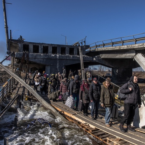 Πρόσφυγες στην Ουκρανία προσπαθούν να διασχίσουν δρόμο κάτω από βομβαρδισμένη γέφυρα