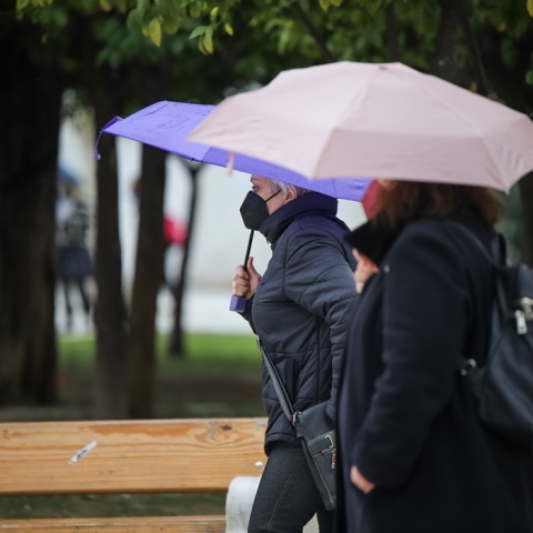 Γυναίκες περπατούν στο κέντρο της Αθήνας κρατώντας ομπρέλες