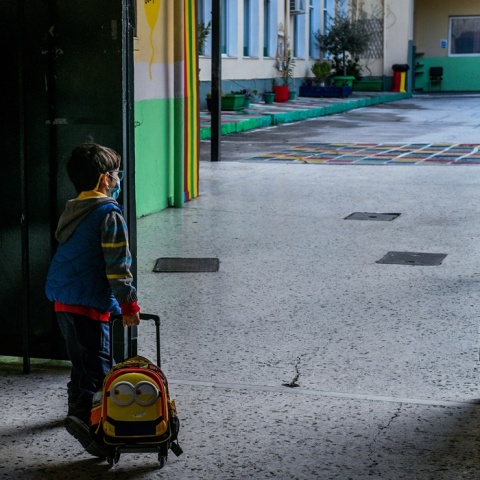 Μικρός μαθητής με την τσάντα του περιμένει να μπει στην τάξη του