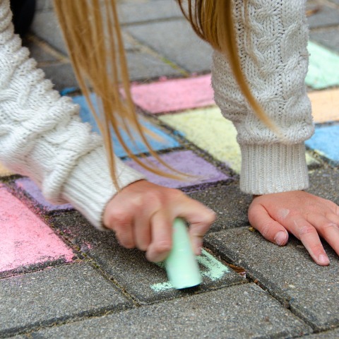 Κοριτσάκι ζωγραφίζει με κιμωλίες στο οδόστρωμα