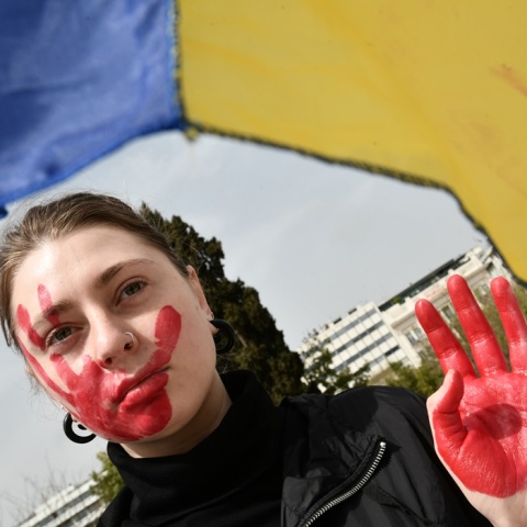 Γυναίκα με κόκκινο στα χέρια και το πρόσωπο συμβολίζει το αίμα που έχει χυθεί στην Ουκρανία