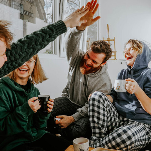 Άντρες και γυναίκες καθισμένοι πίνουν καφέ και γελούν