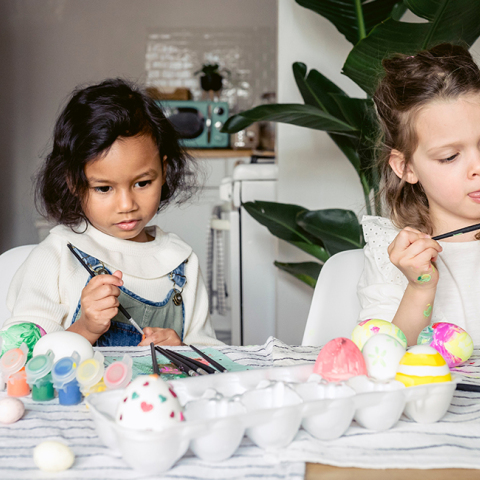 Δύο μικρά κοριτσάκια βάφουν πασχαλινά αυγά