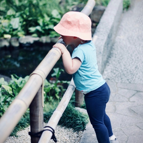 Κοριτσάκι φορά το καπέλο του και κοιτά πάνω από γέφυρα