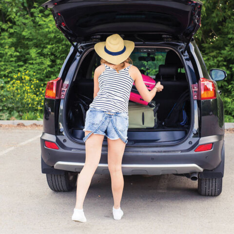 Φωτογραφία μίας γυναίκας να τοποθετεί τα πράγματά της στο πόρτμπαγκάζ.