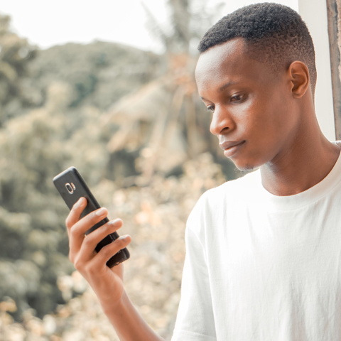 Μια φωτογραία ενός άνδρα να κρατάει ένα κινητό τηλέφωνο.