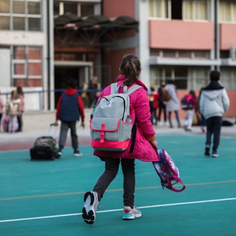 Σχολείο: Μικρή μαθήτρια φορά τη σχολική της τσάντα και κρατά την τσάντα με το φαγητό της
