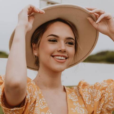 Νεαρή κοπέλα που φοράει καπέλο και χαμογελάει