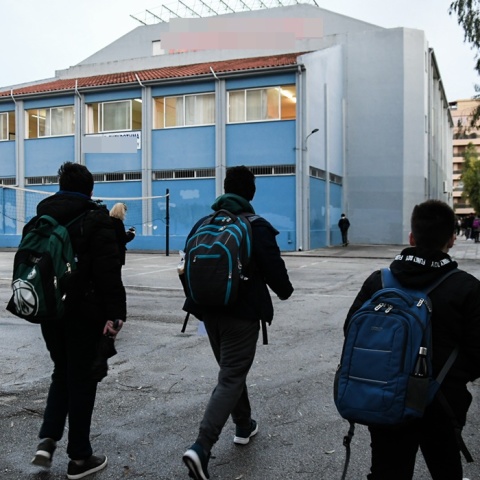 Μαθητές με τις σχολικές τους τσάντες περνούν την είσοδο του σχολείου τους