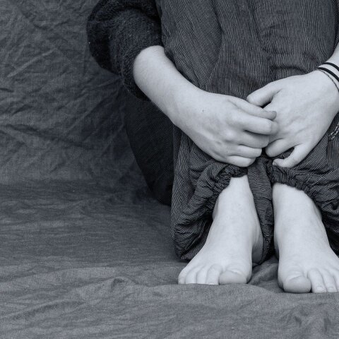 Παιδί καθιστό με σταυρωμένα χέρια μπροστά από τα πόδια - Δεν φαίνεται το πρόσωπό του - Εικόνα που παραπέμπει σε bullying ή κακοποίηση