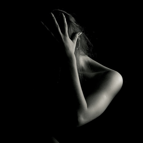 Γυναίκα φωτογραφίζεται με το χέρι στο πρόσωπο σε σκοτάδι - Φαίνεται ο ώμος και το χέρι της