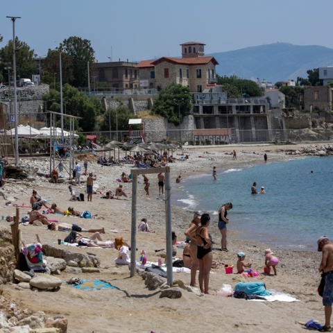 Λουόμενοι σε παραλία απολαμβάνουν την ηλιοθεραπεία τους - Ζέστη στην Αττική τον Μάιο του 2022