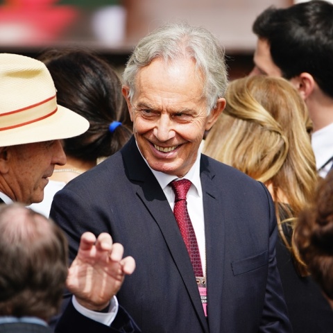 Ο Τόνι Μπλερ στο κέντρο της φωτογραφίας χαμογελά σε συνομιλητή του