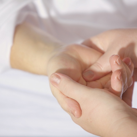 Εικόνα με μία γιατρό να εξετάζει ένα χέρι.