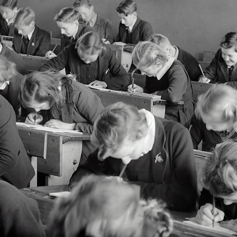 Ασπρόμαυρη φωτογραφία μαθητών σε θρανία να γράφουν διαγώνισμα