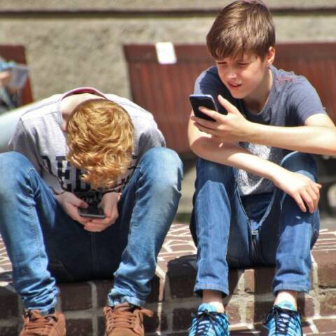 Δύο αγόρια που ασχολούνται με τα κινητά τους