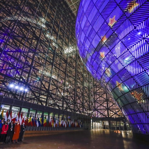 Eurogroup: Πολιτικοί κάτω από το σήμα της Ευρωπαϊκής Ένωσης που προβάλλεται σε κτήριο