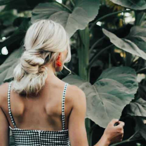 Ξανθιά γυναίκα γυρισμένη πλάτη με μαζεμένα μαλλιά σε χαμηλό κότσο