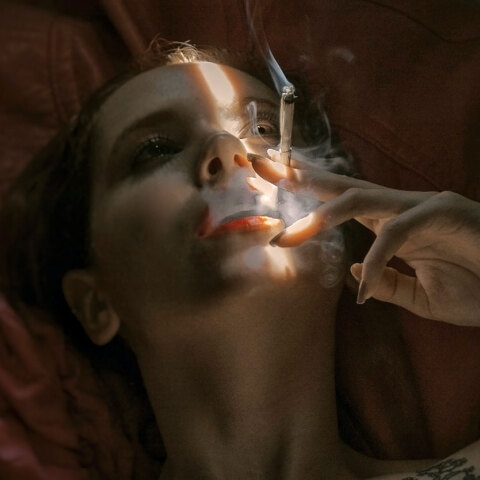 Γυναίκα ξαπλωμένη καπνίζει