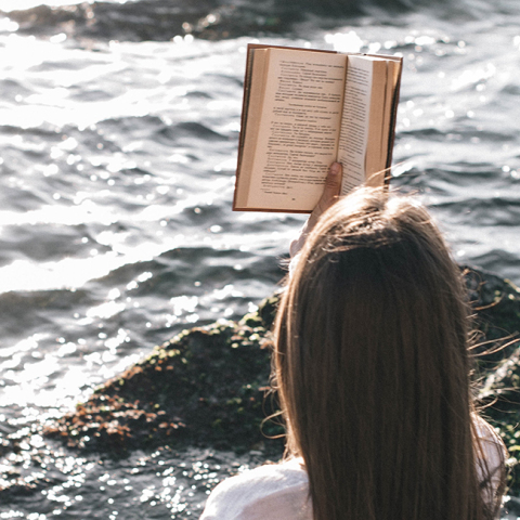 Κοπέλα που διαβάζει βιβλίο στη θάλασσα