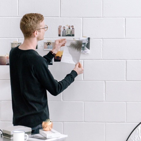 Άνδρας που κολλάει φωτογραφίες σε λευκό τοίχο