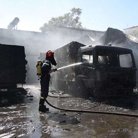 Πυροσβέστης ρίχνει νερό σε φωτιά σε βιοτεχνία στο Μενίδι