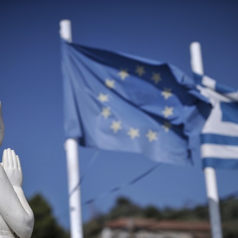 Η σημαία της Ευρωπαϊκής Ένωσης και της Ελλάδας κυματίζουν πίσω από το άγαλμα στο Μνημείο Πεσόντων στην Μηλίνα Πηλίου