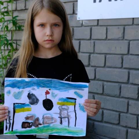Ένα κορίτσι από την Ουκρανία κρατάει μια ζωγραφιά για τον πόλεμο της Ρωσίας στη χώρα της