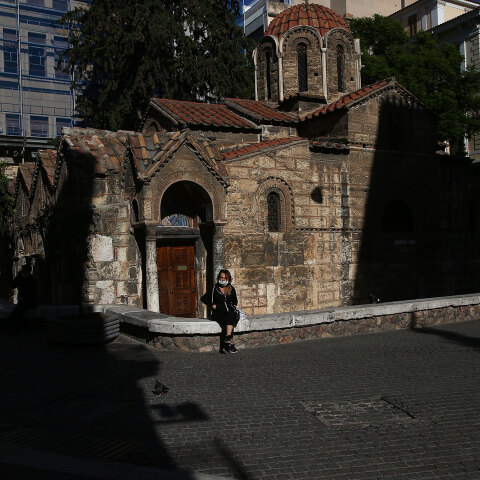 Σκληρό lockdown στην Αττική για τον κορωνοϊό έως τις 28 Φεβρουαρίου 2021 - Κοπέλα με μάσκα κάθεται στο πεζούλι μπροστά από την Καπνικαρέα, την ιστορική εκκλησία στην Ερμού
