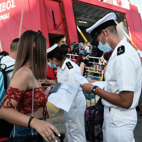 Ταξιδιώτες αναμένουν την επιβίβασή τους σε πλοίο κρατώντας στα χέρια κινητό ή έγγραφα που χρειάζονται 