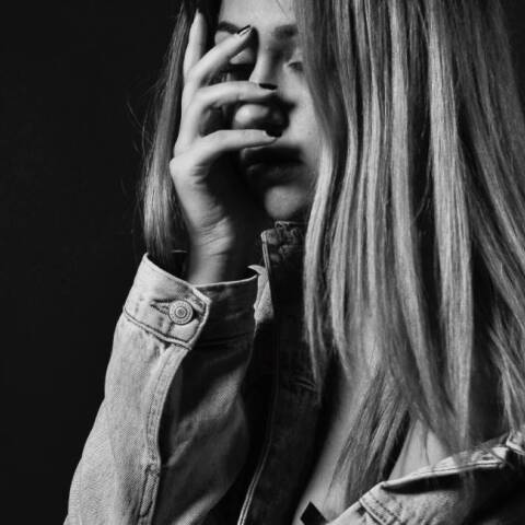 Ασπρόμαυρη φωτογραφία κοπέλας που κρύβει το πρόσωπό της με το χέρι της