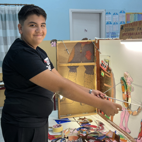 Ο Χρυσοβαλάντης Καραγιαννόπουλος με τις φιγούρες Καραγκιόζη πίσω από τον μπερντέ