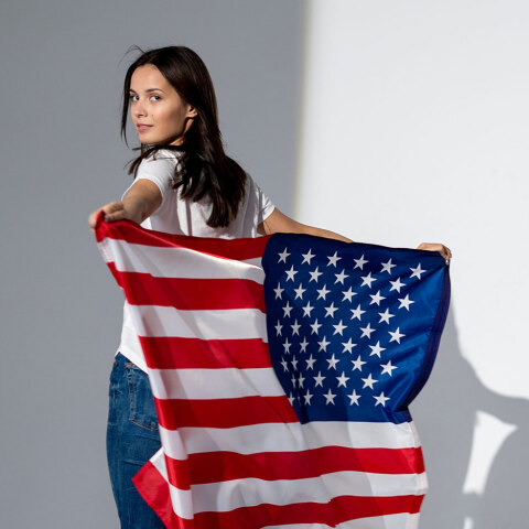 Γυναίκα με λευκό μπλουζάκι και τζιν, που κρατάει την αμερικάνικη σημαία
