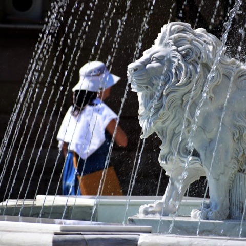 Λιοντάρι σε σιντριβάνι και γυναίκα με καπέλο προστατεύεται από τον καύσωνα
