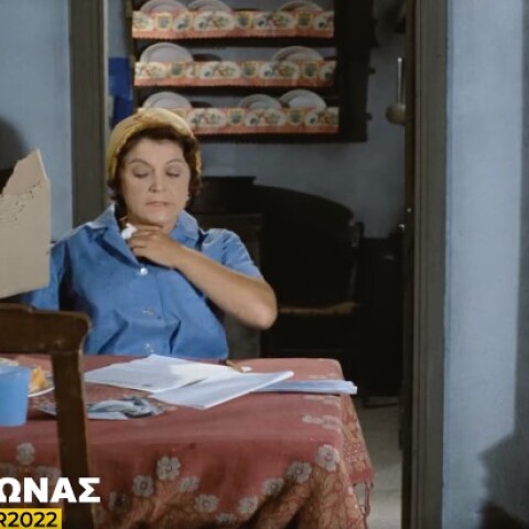 Η Ρένα Βλαχοπούλου κάνει αέρα με ένα χαρτόνι και κρατά ένα χαρτί για να σκουπίσει τον ιδρώτα της